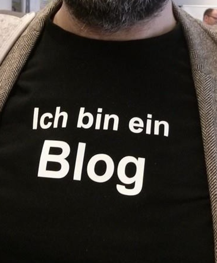 Brustbild von Robert Lender, die ein T-Shirt mit der Aufschrift "Ich bin ein Blog" trägt.