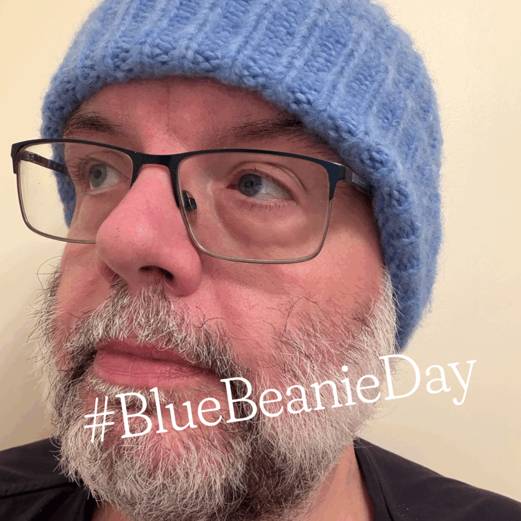 Profilbild von Robert Lender mit blauer Haube. Schrift "#BlueBeanieDay"