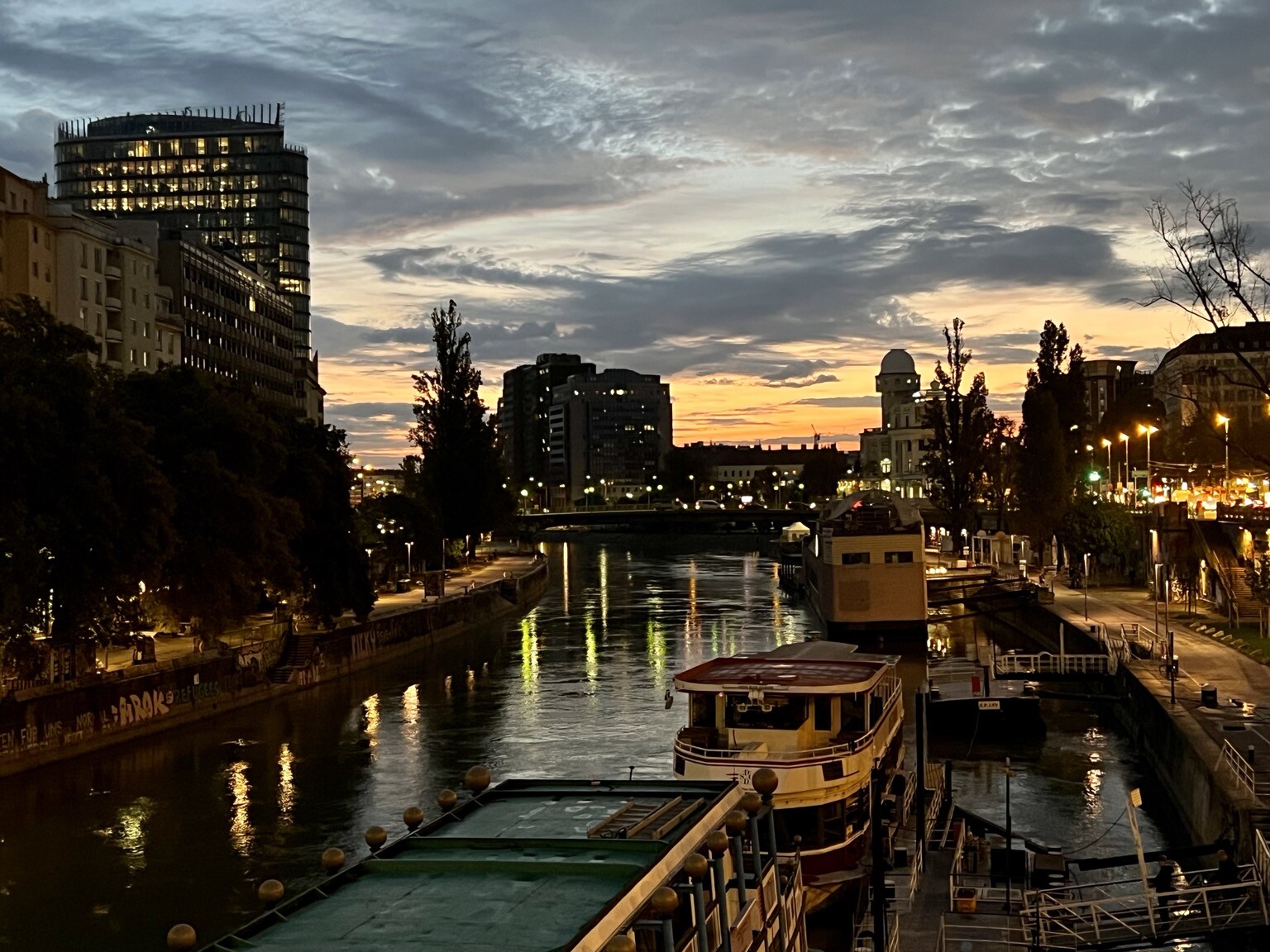 Donaukanal am Morgen, Häuserfront, Himmel teilweise bewölkt, Sonne am aufgehen.