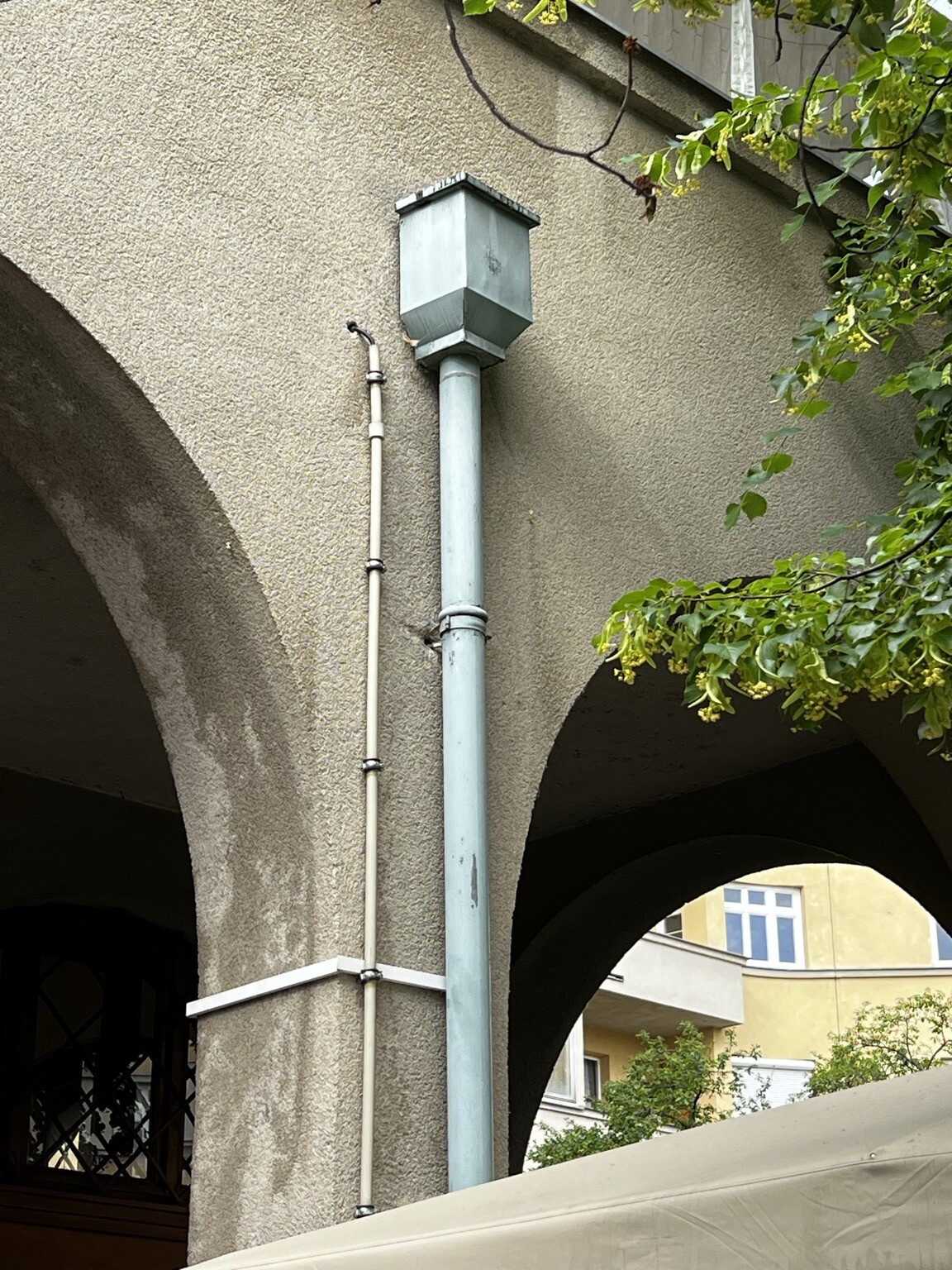 Torbögen. An der Mauer führt ein dünnes Rohr mit einer Elektroleitung und ein Wasserrohr in die Höhe