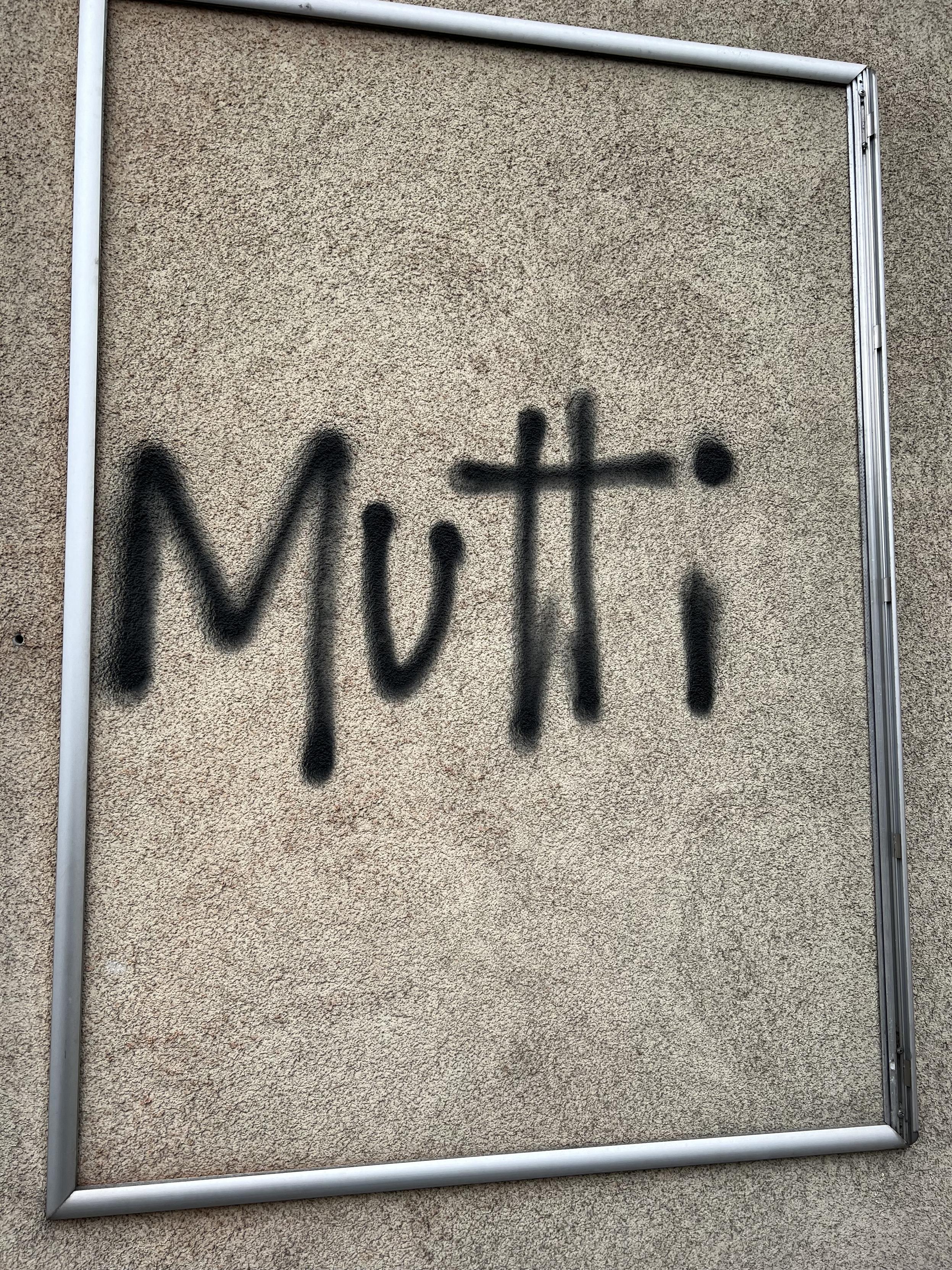 Mauer an einem Gebäude. Leerer Rahmen. Innnerhalb diesem der Schriftzug (Graffiti) „Mutti“. 