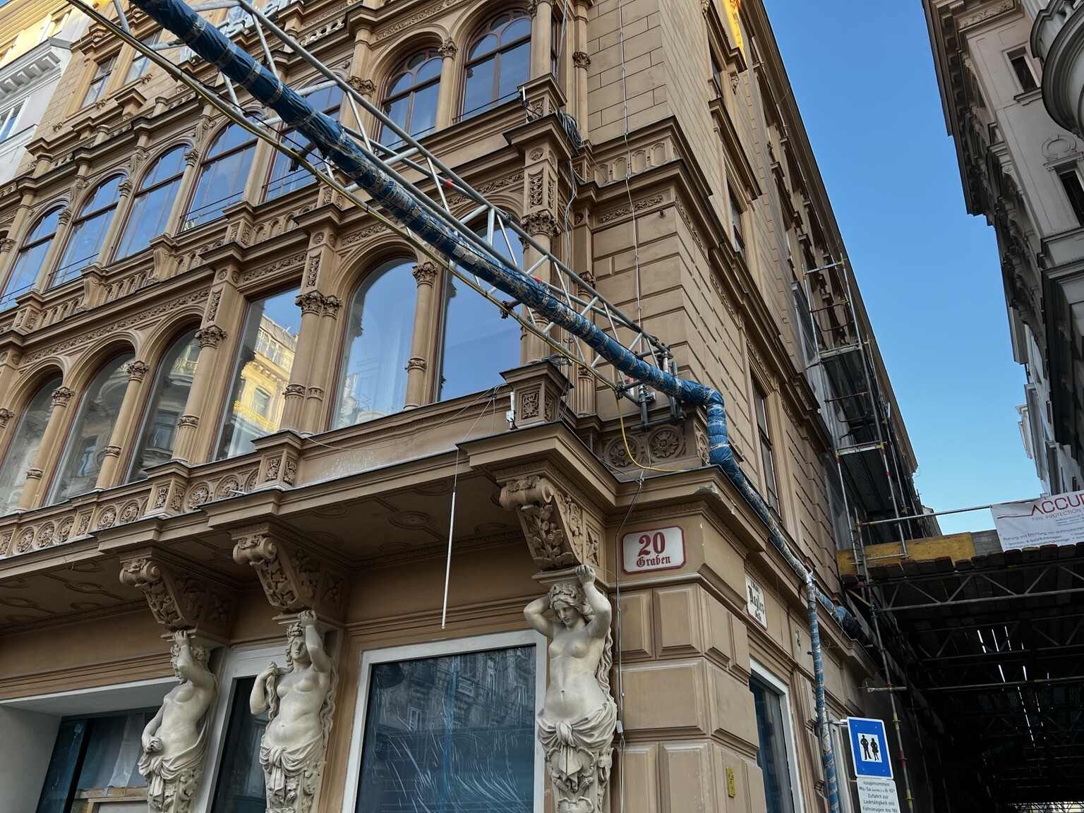 Rohrleitung oberhalb einer Straße zu einem Gebäude führend und dort an der Mauer entlanglaufend