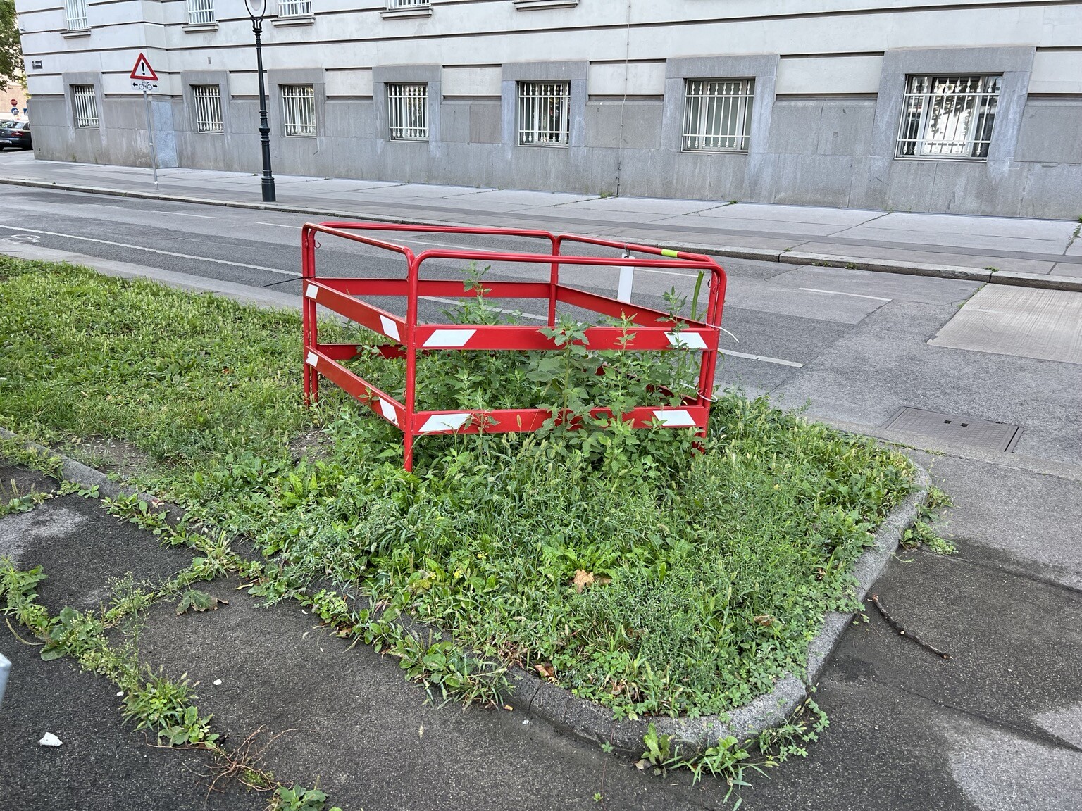 Rasenstreifen neben Fahrbahn. Ein kleines Stück ist mit einer rautenförmigen Absperrung versehen.