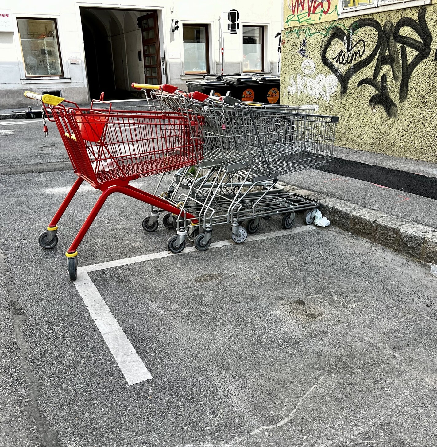 Ineinandergeschobene Einkaufswagen auf der Straße stehend. Dahinter ein roter Einkaufswagen