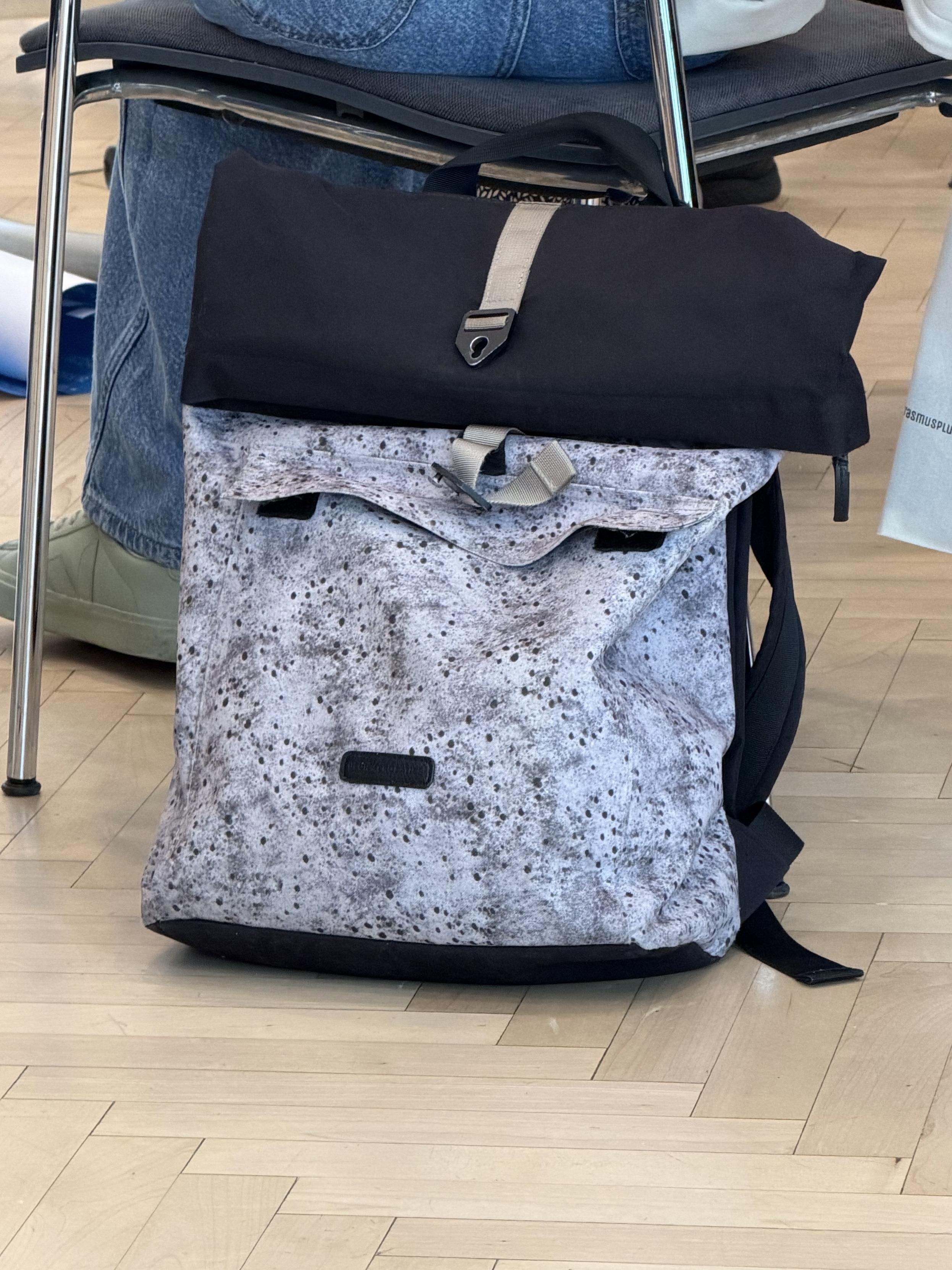 Tasche an einem Sessel gelehnt. Die Verschlüsse wirken so als wenn sie Augen und Mund bilden,