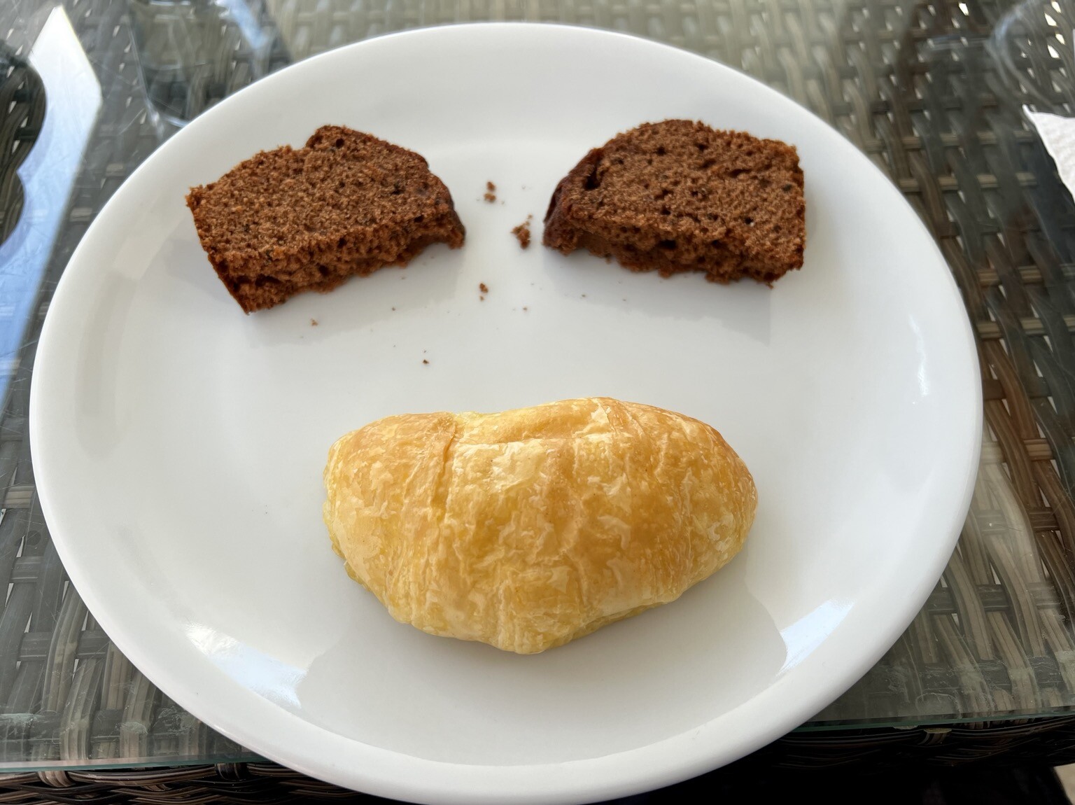 Teller auf dem zwei Kuchenstücke und ein Kipferl so liegen, dass sie einen Smiley ähnlich sehen.