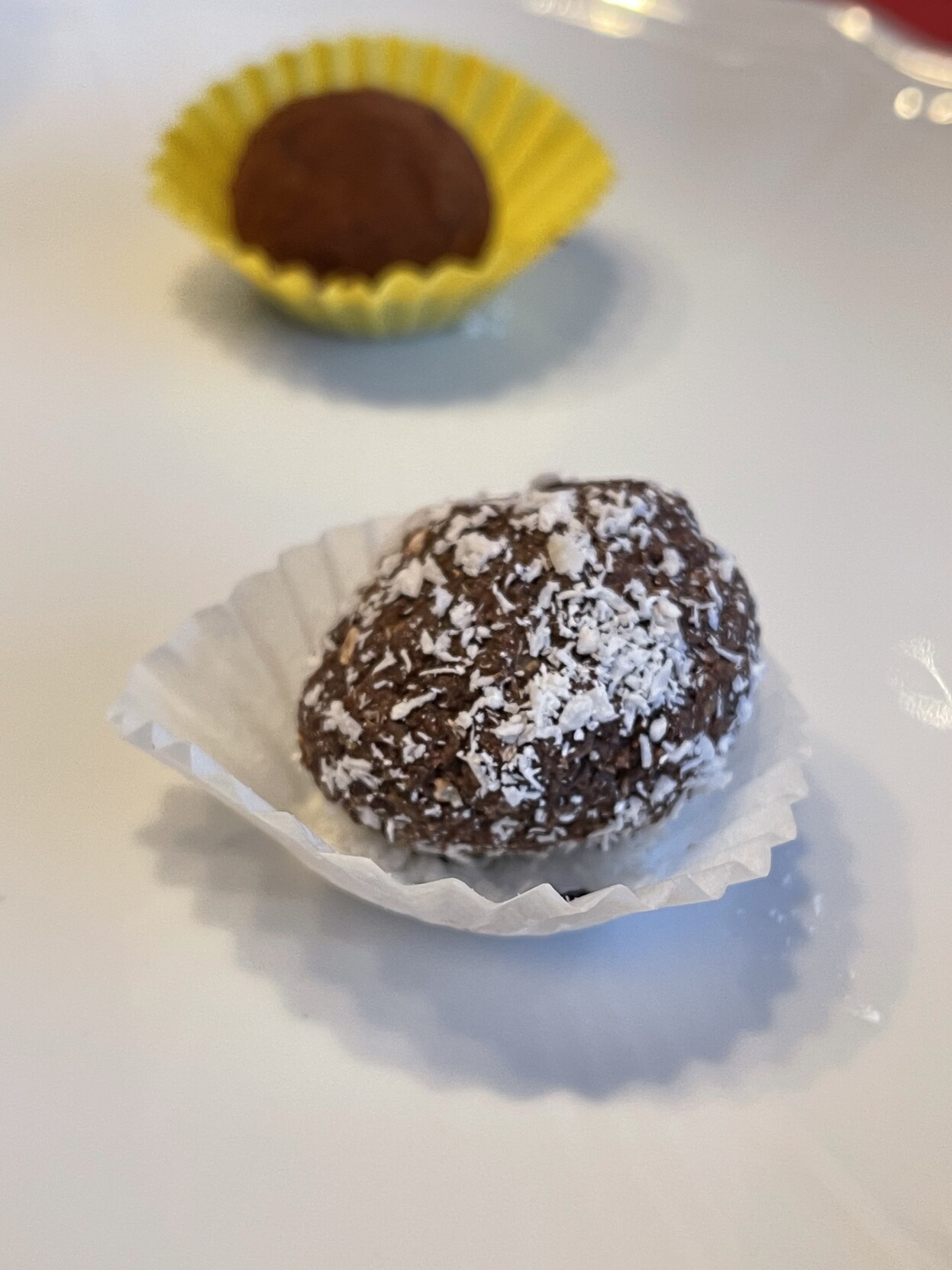 Rumkugeln mit Streusel in einer kleinen Papierschale. Weiter hinten noch eine weitere. 