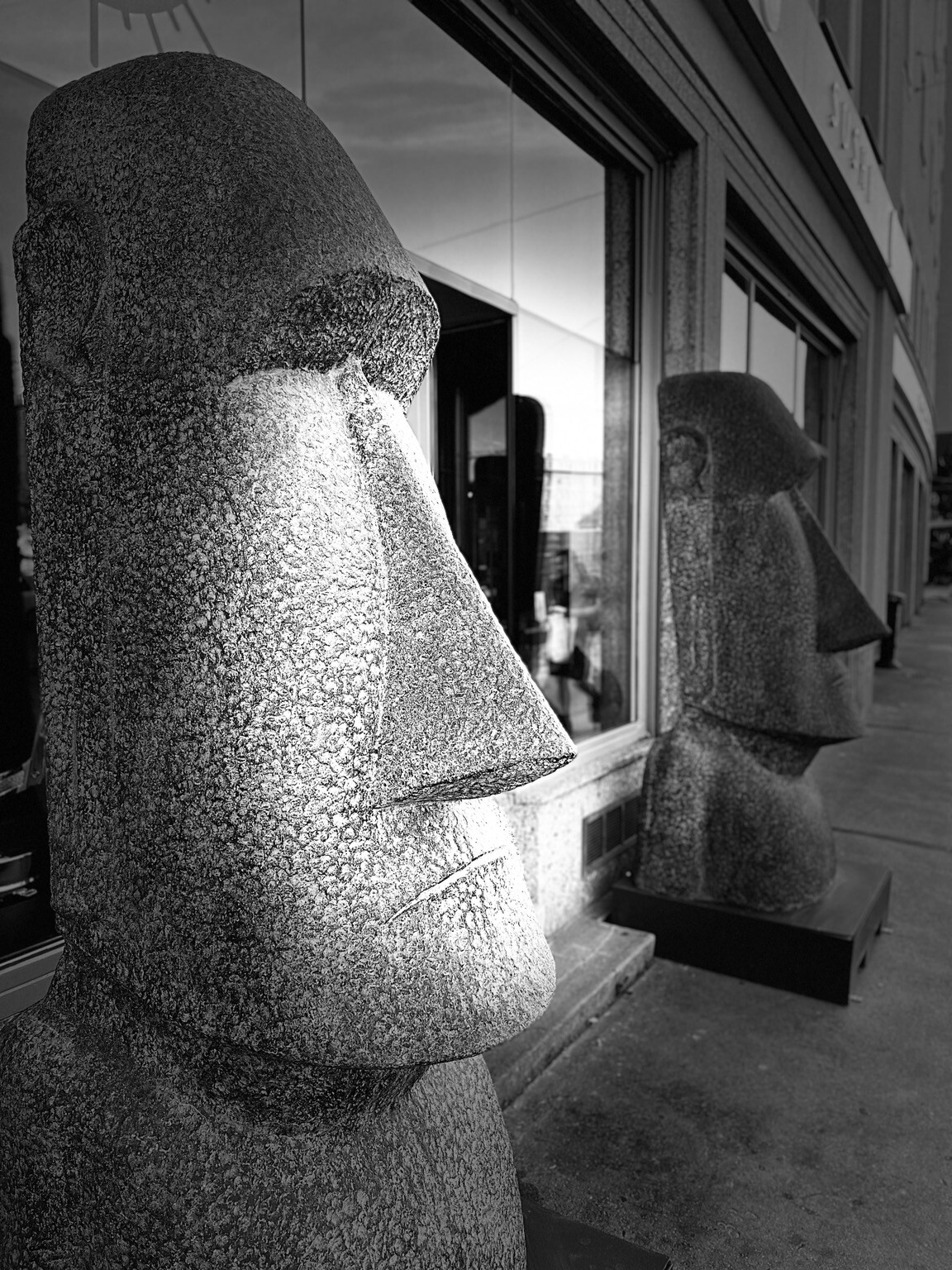 Rund zwei große Osterinsel Skulpturen (Moai) vor einer Auslage