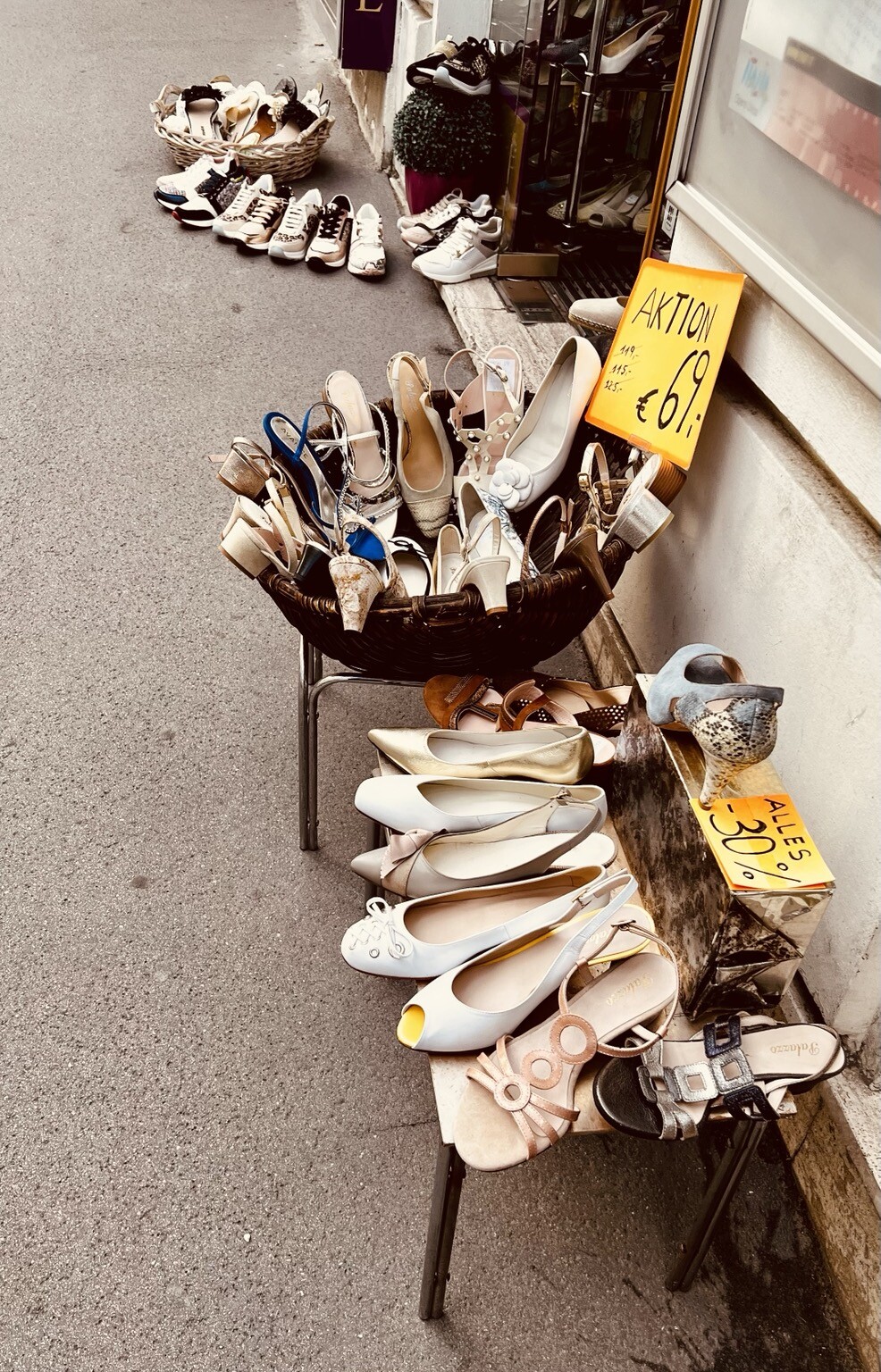 Vor Geschäft unzählige Schuhe am Gehsteig in Reihen oder in Körben.