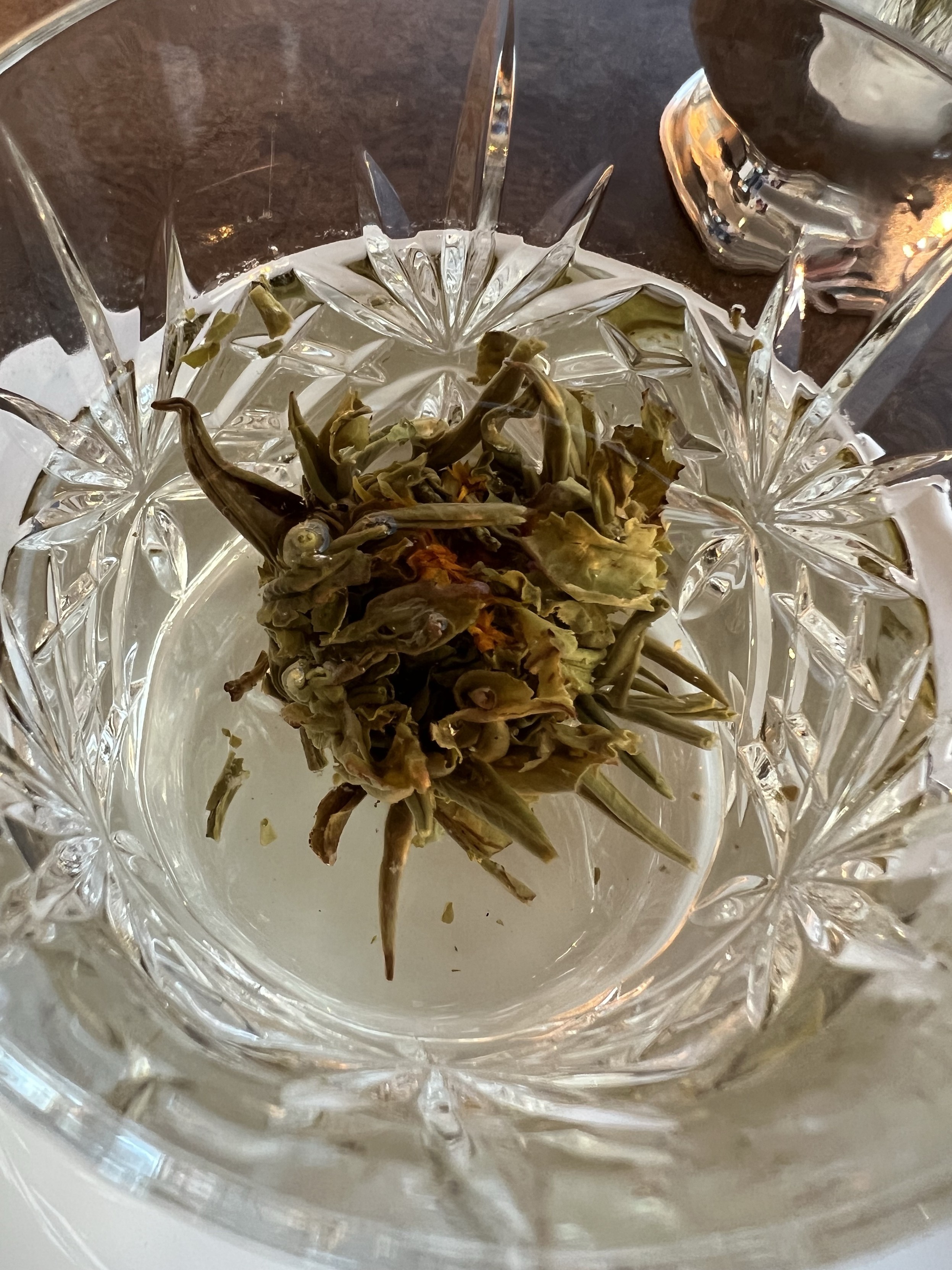 Eine Nahaufnahme einer blühenden Teeblume in einer Kristallglastasse.