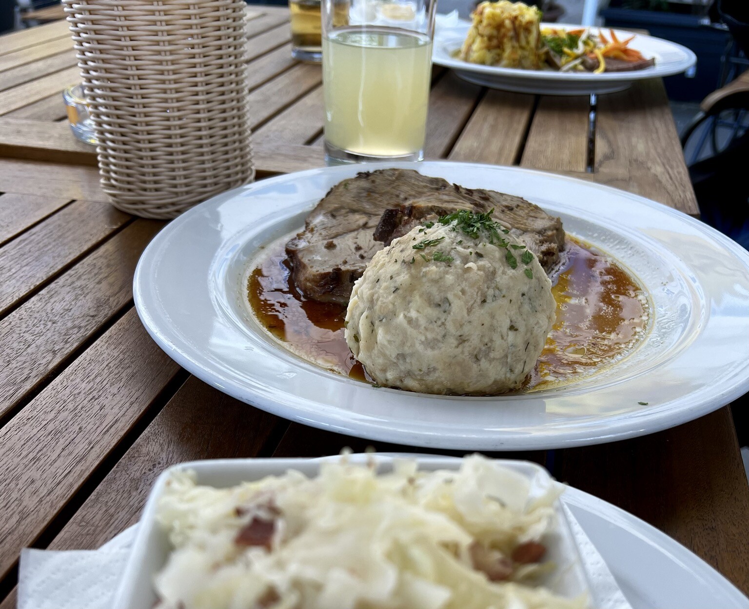 Tisch. Teller. Knödel. Dahinter Schweinsbraten